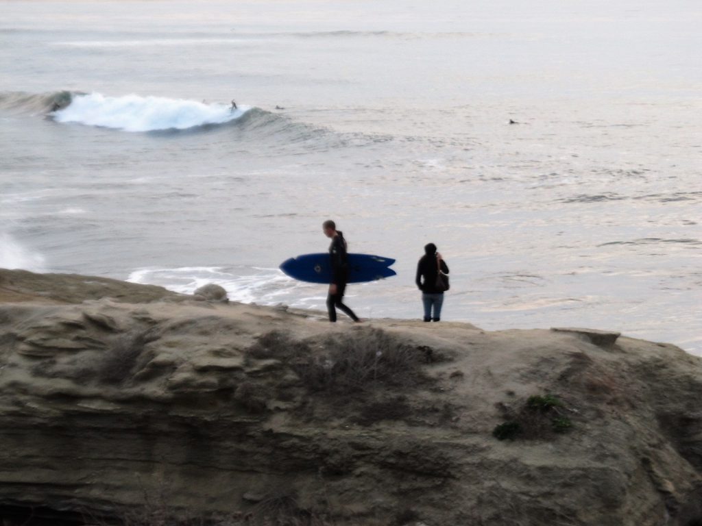 surfer and person walking bluff, ocean background