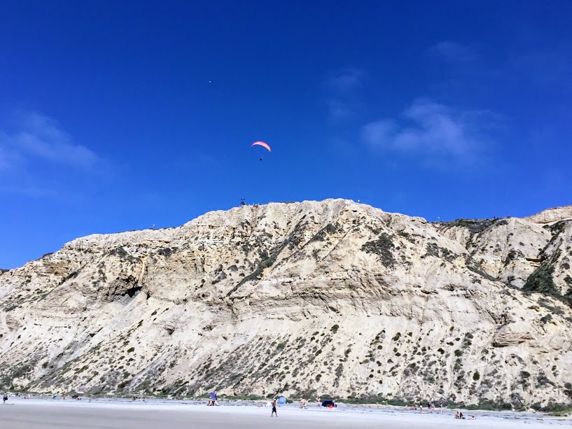 Paraglider Blacks Beach cliffs people sand