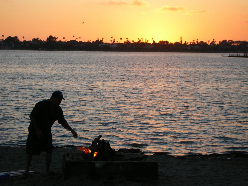 fiesta island sunset man bonfire water